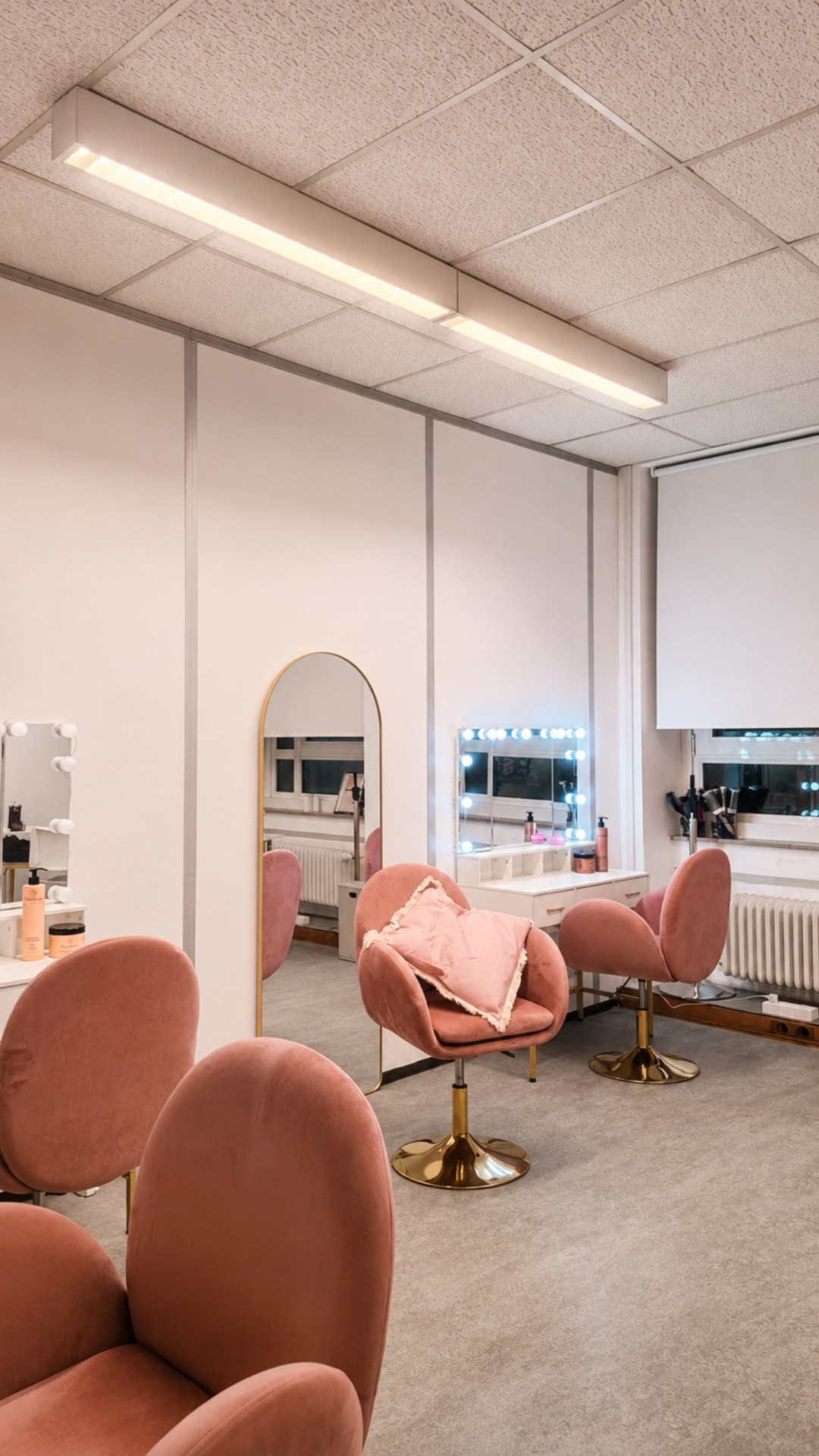 Salon de coiffure avec fauteuils roses et miroirs lumineux